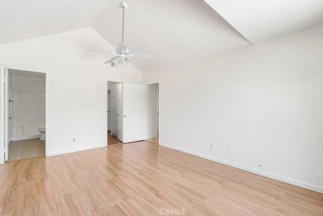 unfurnished bedroom featuring high vaulted ceiling, light wood finished floors, baseboards, and ensuite bathroom