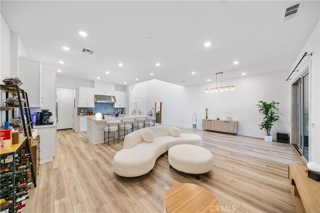 living room featuring light wood-style floors, recessed lighting, and visible vents
