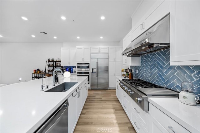 kitchen with white cabinetry, under cabinet range hood, visible vents, appliances with stainless steel finishes, and a sink