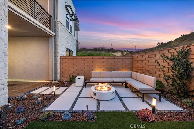 patio terrace at dusk with an outdoor living space with a fire pit and a fenced backyard