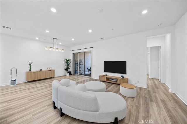 living room featuring light wood-type flooring, baseboards, and visible vents