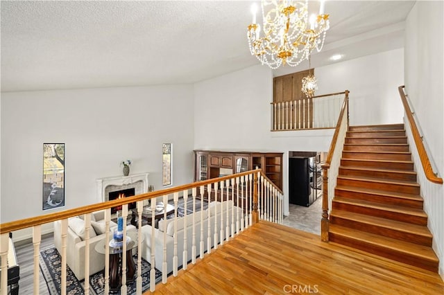 41018 40th St W, Palmdale, CA 93551 - staircase featuring a chandelier, a warm lit fireplace, wood finished floors, and a textured ceiling