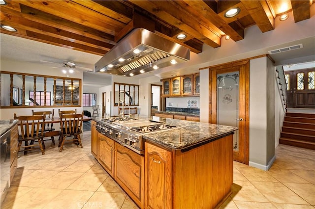 41018 40th St W, Palmdale, CA 93551 - kitchen featuring island exhaust hood, stainless steel gas cooktop, light tile patterned floors, a center island, and glass insert cabinets