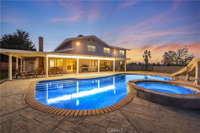 41018 40th St W, Palmdale, CA 93551 - pool at dusk featuring an in-ground hot tub, a water slide, a patio area, and a grill