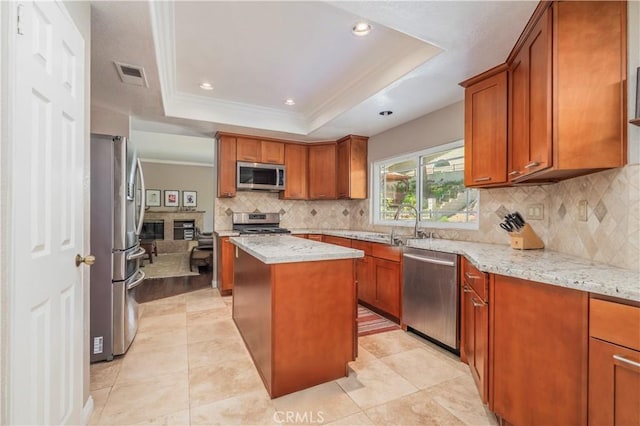 kitchen with visible vents, a center island, appliances with stainless steel finishes, a raised ceiling, and brown cabinets