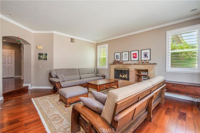 living room with dark wood-style flooring, visible vents, arched walkways, and crown molding