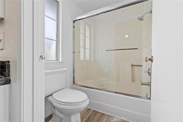full bathroom with toilet, wood finished floors, and combined bath / shower with glass door
