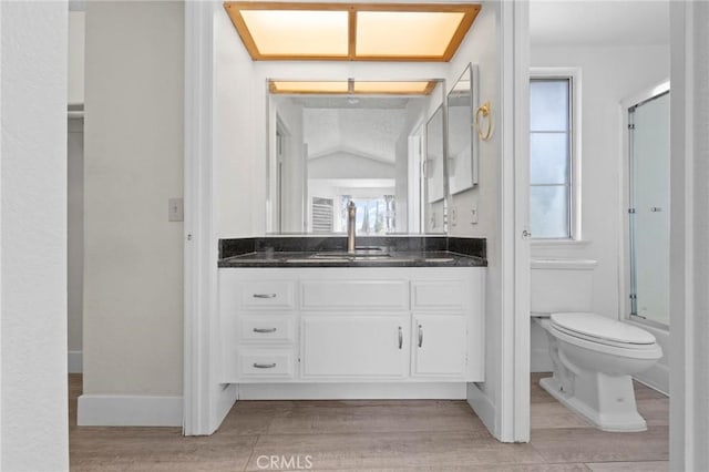 bathroom with an enclosed shower, toilet, a wealth of natural light, and vanity