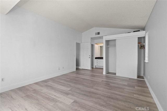 unfurnished bedroom featuring wood finished floors, visible vents, and lofted ceiling