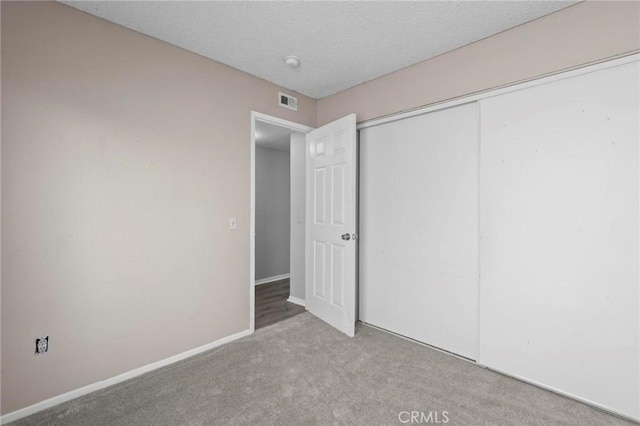 unfurnished bedroom featuring a closet, baseboards, carpet flooring, a textured ceiling, and visible vents
