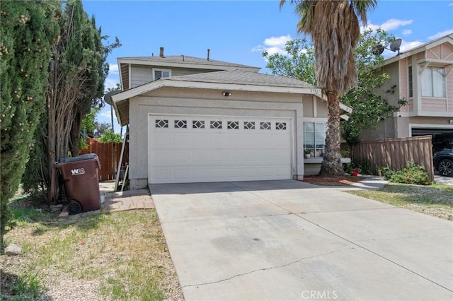view of front of house featuring driveway, a garage, and fence