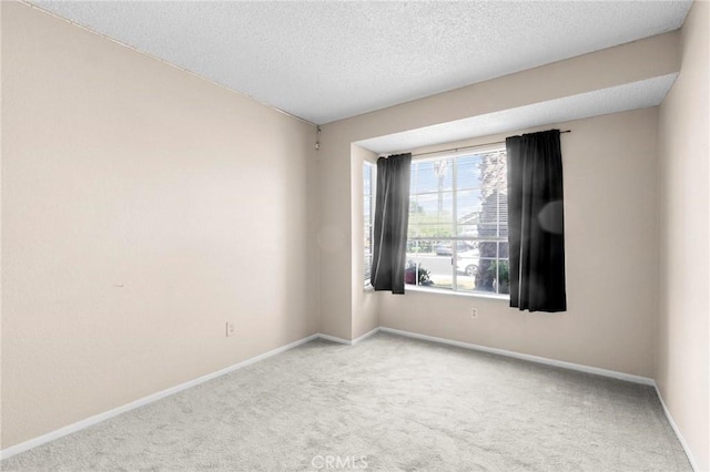 spare room with carpet floors, baseboards, and a textured ceiling