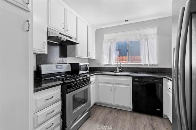 kitchen featuring white cabinetry, appliances with stainless steel finishes, under cabinet range hood, dark countertops, and a sink