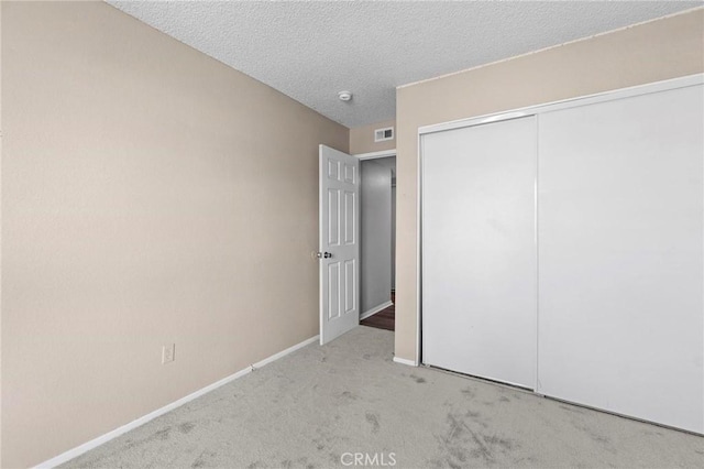 unfurnished bedroom featuring a closet, baseboards, a textured ceiling, visible vents, and carpet