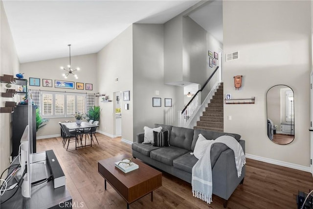 living area featuring visible vents, stairs, wood finished floors, high vaulted ceiling, and a chandelier