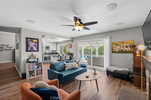 living room featuring baseboards, ceiling fan, and wood finished floors