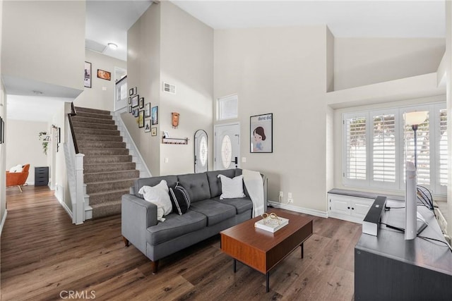 living room featuring visible vents, wood finished floors, stairway, baseboards, and a high ceiling