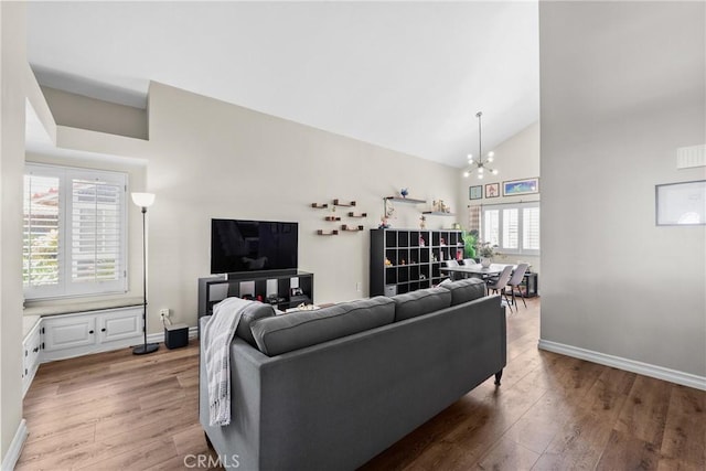 living area with baseboards, an inviting chandelier, and wood finished floors