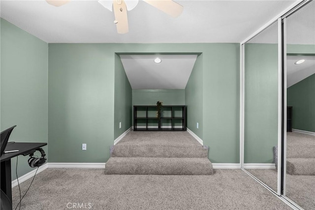 stairway with baseboards, a ceiling fan, and carpet flooring