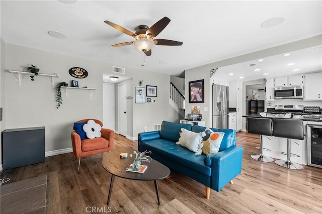 living area with ceiling fan, visible vents, stairs, wood finished floors, and recessed lighting