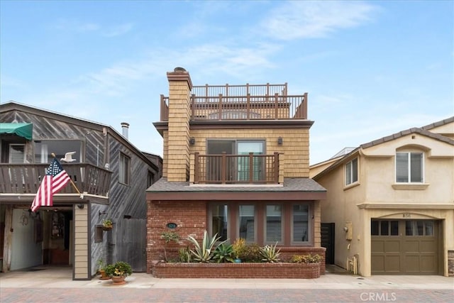 57 B Surfside Ave, Surfside, CA 90743 - view of front facade with a balcony, brick siding, a chimney, a garage, and driveway