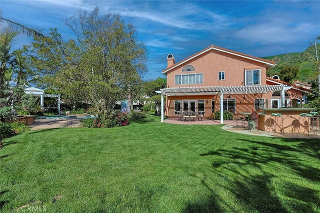 back of house featuring a patio, outdoor dry bar, a pergola, and a lawn