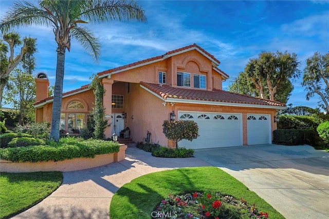 mediterranean / spanish house with concrete driveway, stucco siding, and a tile roof