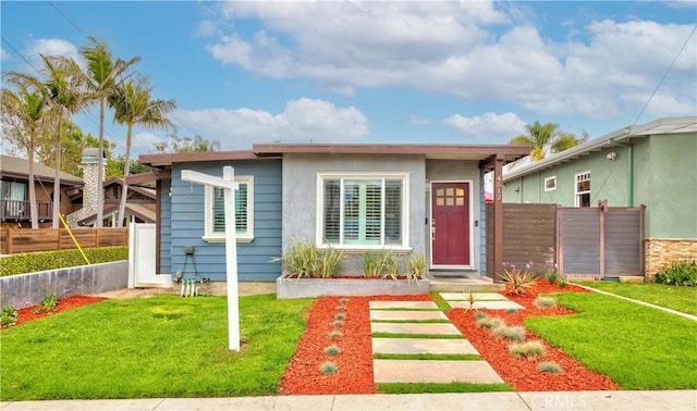 bungalow-style home featuring fence, a front yard, and stucco siding