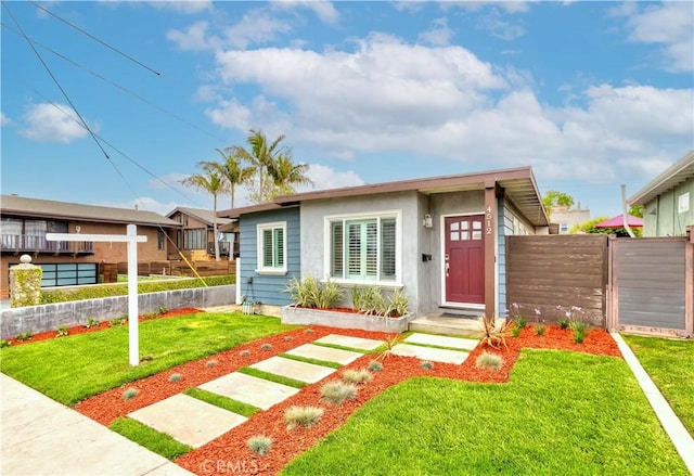 view of front of house featuring stucco siding, a front lawn, and fence