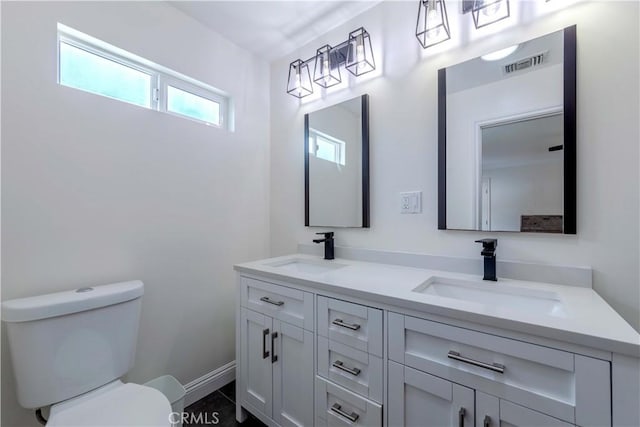 bathroom with visible vents, a sink, double vanity, and toilet