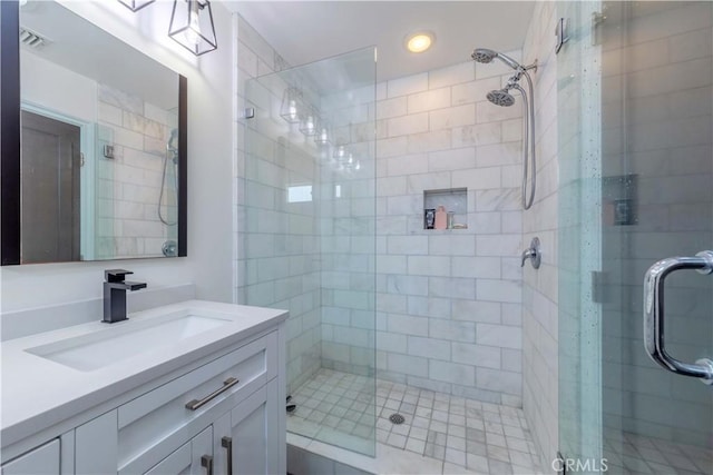 bathroom with a shower stall, vanity, and visible vents