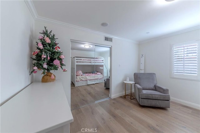 living area with baseboards, ornamental molding, light wood-style floors, and visible vents