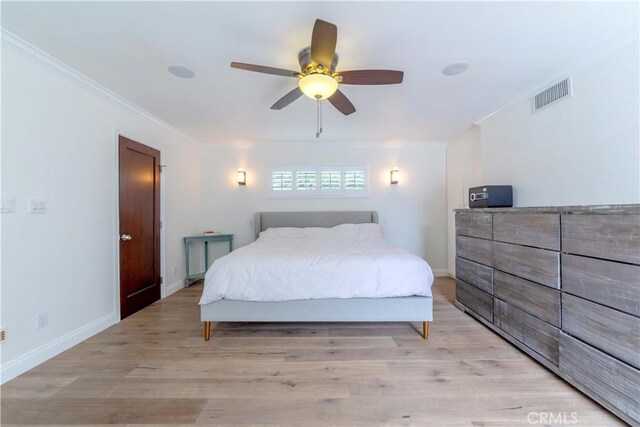 bedroom featuring baseboards, visible vents, light wood-style floors, and ornamental molding