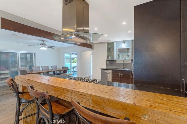 kitchen featuring a sink, island range hood, glass insert cabinets, appliances with stainless steel finishes, and recessed lighting
