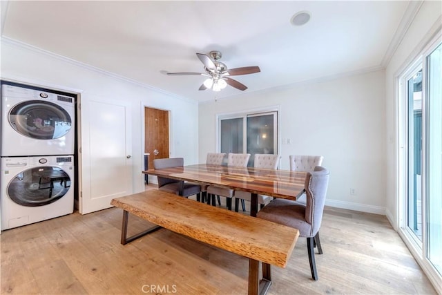 dining space with stacked washer / drying machine, light wood-style flooring, and crown molding