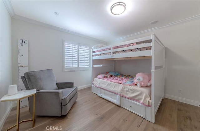 bedroom with baseboards, crown molding, and light wood-type flooring
