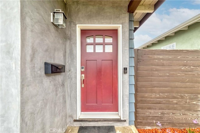 view of exterior entry featuring fence and stucco siding