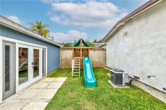 view of yard with central air condition unit, fence, a playground, and french doors