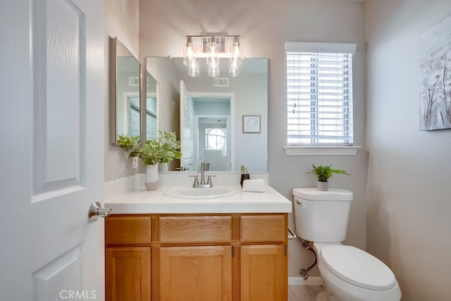 bathroom with toilet, a chandelier, and vanity