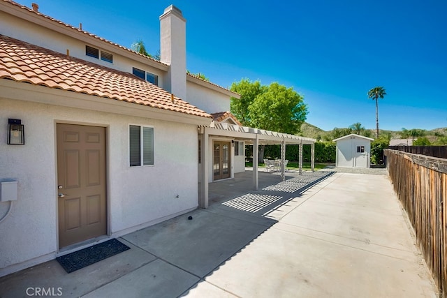 rear view of house with a shed, a patio, stucco siding, fence, and a pergola