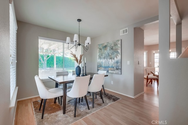 dining area featuring a chandelier, wood finished floors, and baseboards