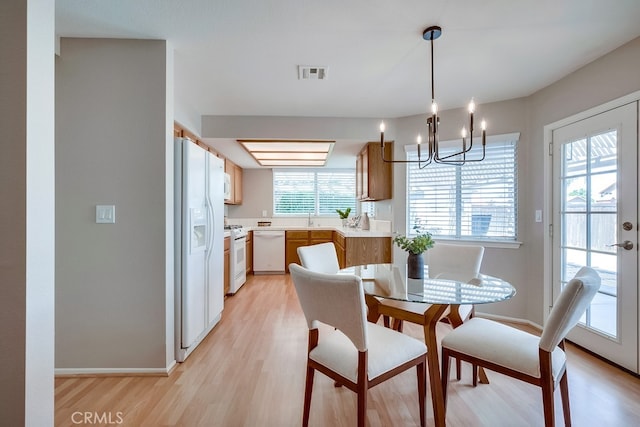 dining room featuring light wood-type flooring, a chandelier, and baseboards