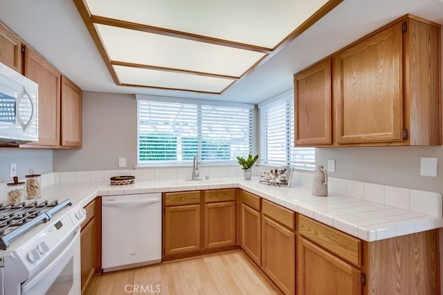 kitchen with white appliances, healthy amount of natural light, light wood-style floors, and a sink