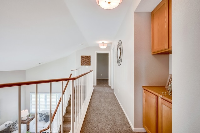 corridor with carpet flooring, lofted ceiling, and an upstairs landing