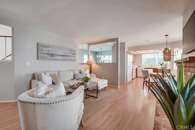 living room featuring a chandelier, light wood finished floors, and baseboards