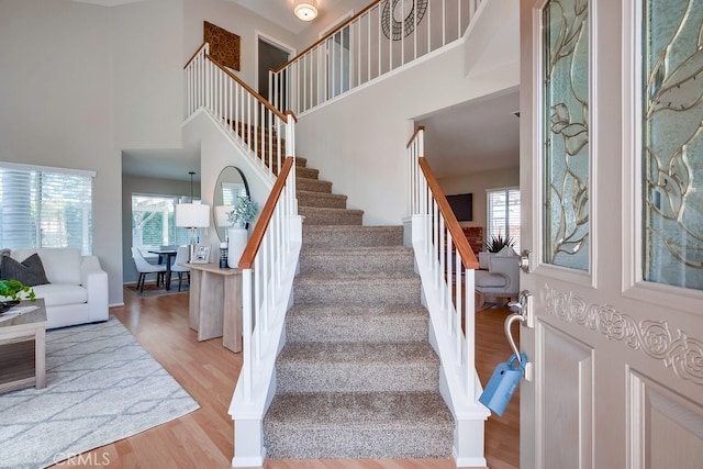 stairway with a high ceiling, wood finished floors, and baseboards