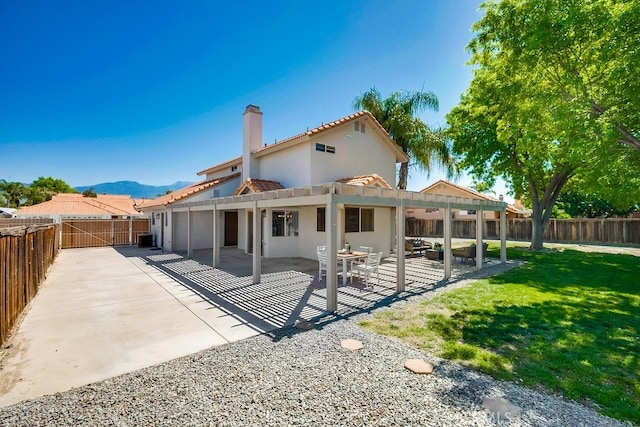 rear view of property featuring stucco siding, a patio area, a chimney, a mountain view, and a tiled roof