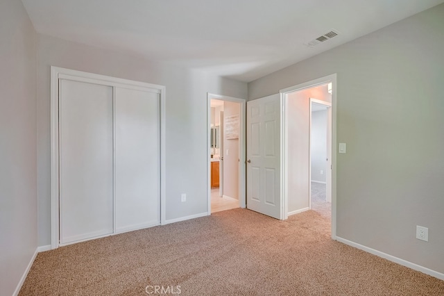 unfurnished bedroom with carpet flooring, baseboards, a closet, and ensuite bath