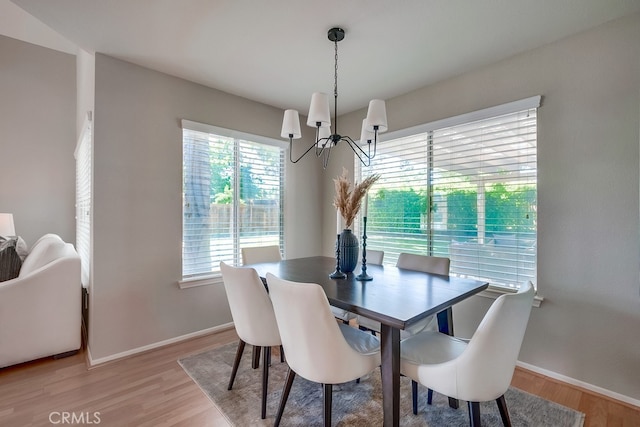 dining area with a chandelier, light wood-style floors, and baseboards