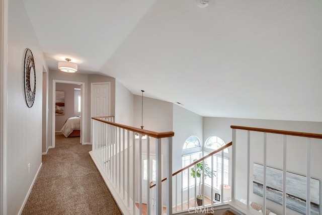 corridor with vaulted ceiling, carpet, and baseboards